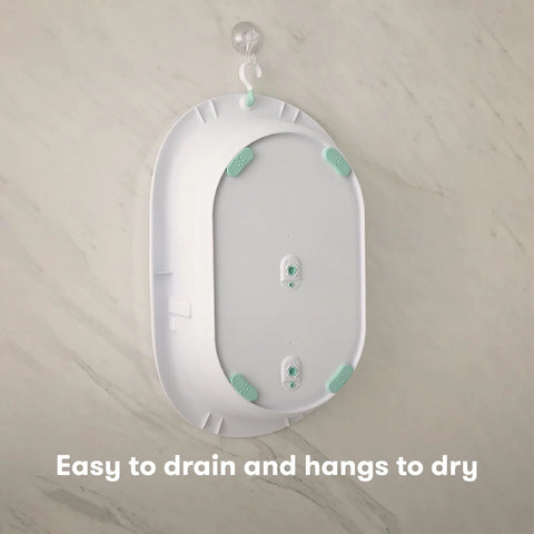 White and green baby changing pad with text 'Easy to drain and hangs to dry' on a beige background