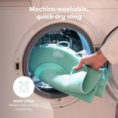 Person holding a green baby sling in front of an open washing machine with text about machine-washable and quick-dry properties.