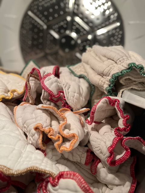 a pile of unbleached cotton fitted diapers freshly washed and fluffy from the dryer