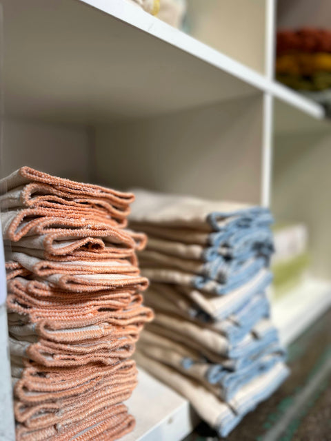 two stacks of soft unbleached cotton prefold diapers neatly folded in a cubby