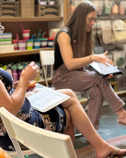 Two women sitting in a store with products in the background, learning how to build a baby registry.